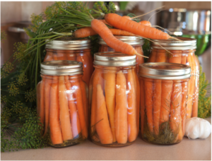 Home canned carrots with raw carrots on top of the cans